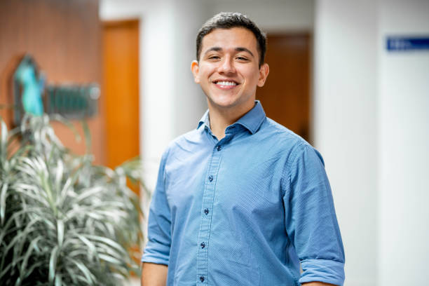 Portrait of a confident young businessman smiling while standing alone in the hallway of a modern office