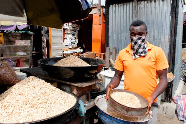 A man using handkerchief as facemask displays his melon inside Mile 12 Food Market in Lagos, Nigeria on Monday, May, 4 2020. In order to cushion the hardship of Coronavirus (COVID-19) pandemic lockdown, government has relaxed its rules by allowing people to move and open business in the day time, imposed curfew form 8PM -6AM and made it compulsory for everybody to wear facemask in public places from Monday, May 4, 2020. Photo by Adekunle Ajayi (Photo by Adekunle Ajayi/NurPhoto via Getty Images)